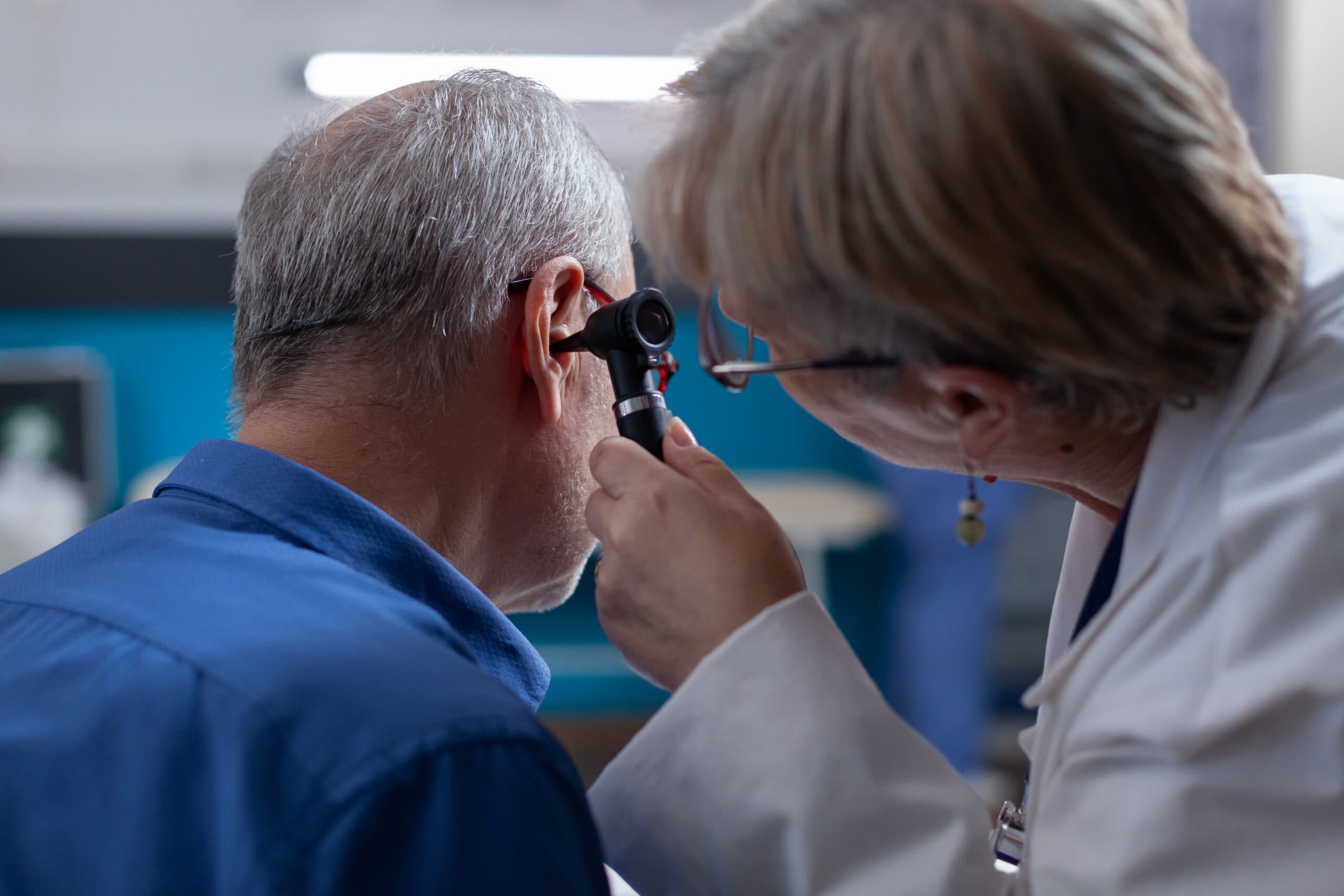 Doctora sosteniendo un otoscopio para realizar una consulta de oído a un anciano en una cita médica