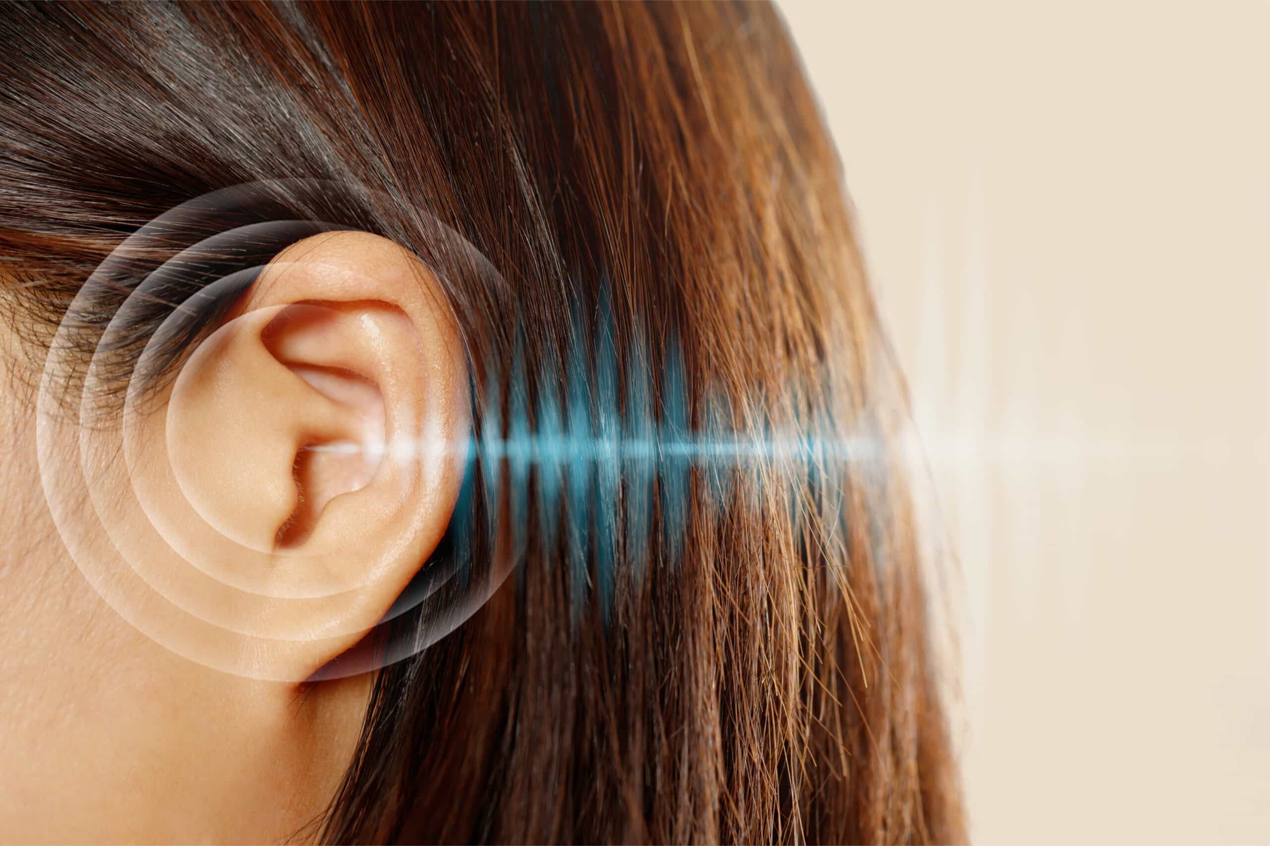 Primer plano del oído de una persona con ondas sonoras ilustradas, que simbolizan la audición o la transmisión del sonido.
